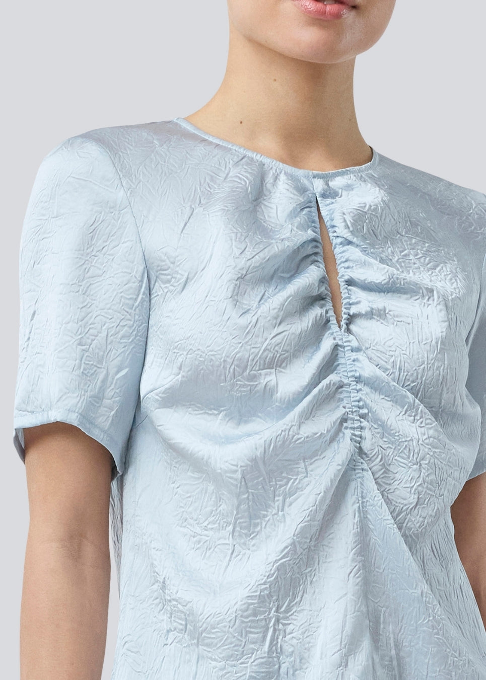 Kortærmet top med rynkedetalje i satin. Parkermd &nbsp;top has en åbning fortil og en usynlig lynlås &nbsp;i ryggen. Modellen er 175 cm og har en str S/36 &nbsp;på.