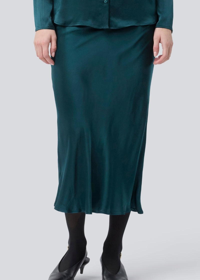 Grøn lang nederdel med vidde i satin. Parveenmd skirt har en elastik i taljen. Modellen er 175 cm og har en str. s/36 på.