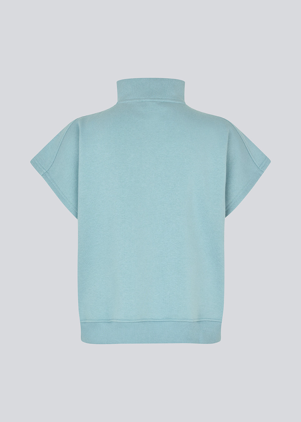 Kortærmet sweatshirt i lyseblå med et sporty twist. PaulaMD SS T-neck har høj hals med lynlås, så du kan vælge mellem et cool højt look eller en mere åben og afslappet stil. Detaljer som brystlogo og ribkant i bunden giver et rent og moderne udtryk.