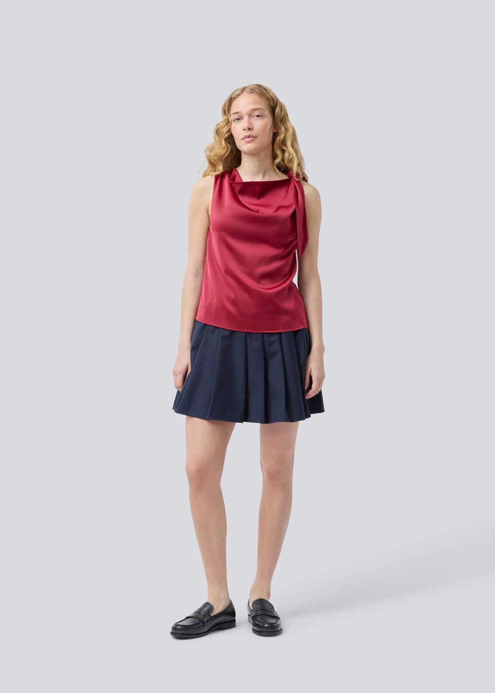 Kort nederdel med læg og mellemhøj talje i mørkeblå. Peggiemd skirt har en usynlig lynlås i siden. Modellen er 175 cm og har en str S/36 på.