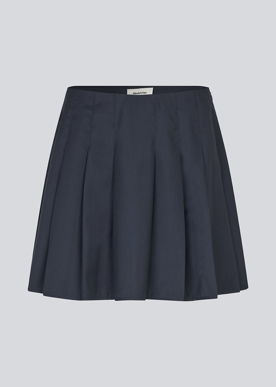 Kort nederdel med læg og mellemhøj talje i mørkeblå. Peggiemd skirt har en usynlig lynlås i siden. Modellen er 175 cm og har en str S/36 på.