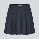 Kort nederdel med læg og mellemhøj talje i mørkeblå. Peggiemd skirt har en usynlig lynlås i siden. Modellen er 175 cm og har en str S/36 på.