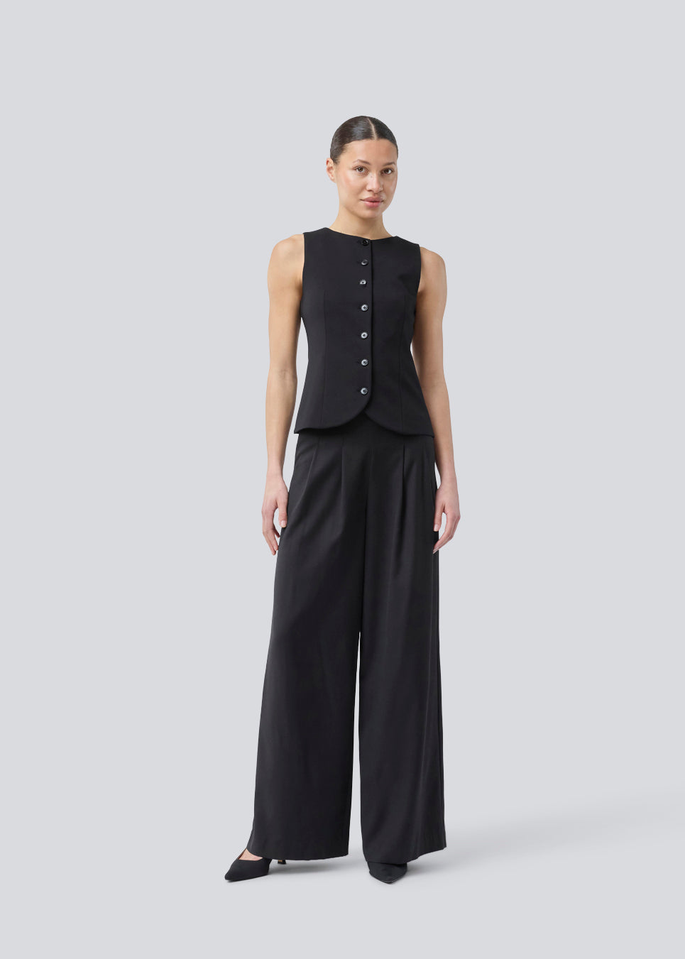 Sorte bukser med brede ben, læg og elastisk talje. Piloumd pants har sidelommer og en lynlås med knappelukning i siden. Modellen er 175 cm og har en str S/36 &nbsp;på.

