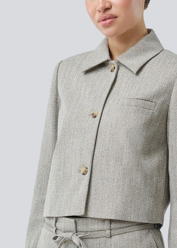 Kort jakke med skjortekrave og knaplukning fortil. Popemd jacket har lange ærmer med slids og en brystlomme. Modellen er 175 cm og har en str. S/36 på.