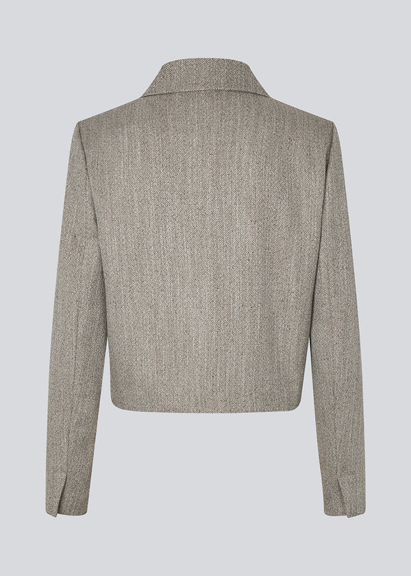 Kort jakke med skjortekrave og knaplukning fortil. Popemd jacket har lange ærmer med slids og en brystlomme. Modellen er 175 cm og har en str. S/36 på.