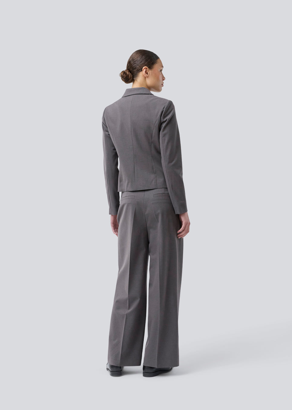 Grå kort figursyet blazer. Primrosemd blazer har knappelukning og to lommer fortil. Modellen er 175 cm og har en str. s/36 på.