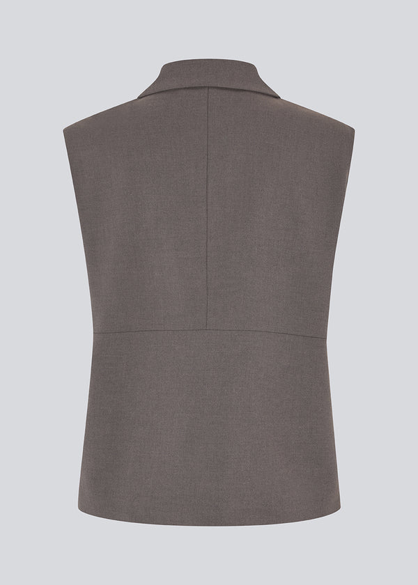 Grå løs vest med skjult knappelukning fortil. Primrosemd vest har en skjortekrave og to forlommer.&nbsp;
