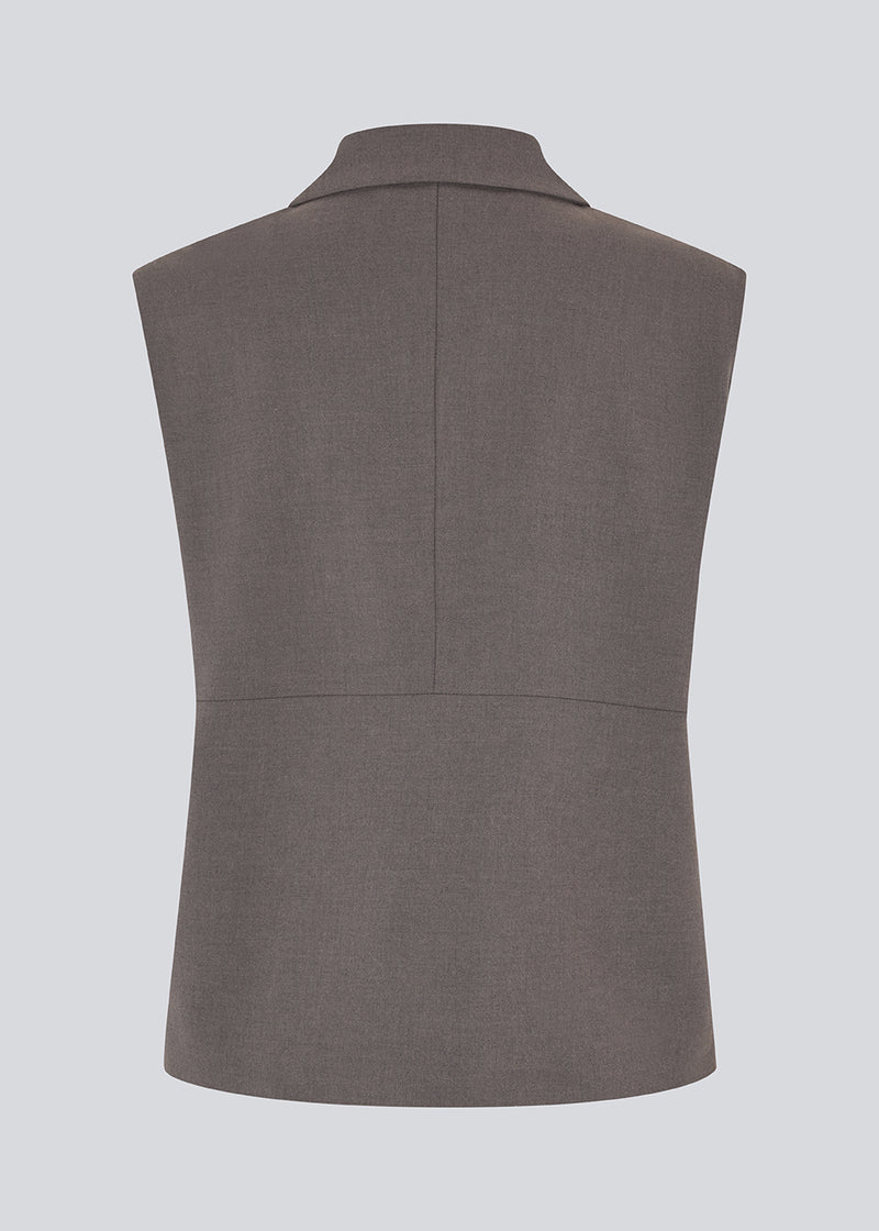 Grå løs vest med skjult knappelukning fortil. Primrosemd vest har en skjortekrave og to forlommer.&nbsp;