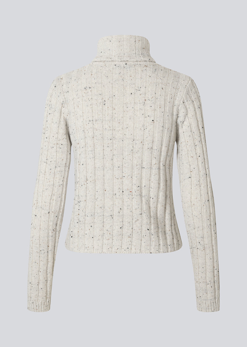 Ribstrikket cardigan med høj hals. Raulmd rollneck cardigan er tætsiddende, stilren og lukkes med lynlås foran – perfekt til et moderne hverdagslook.