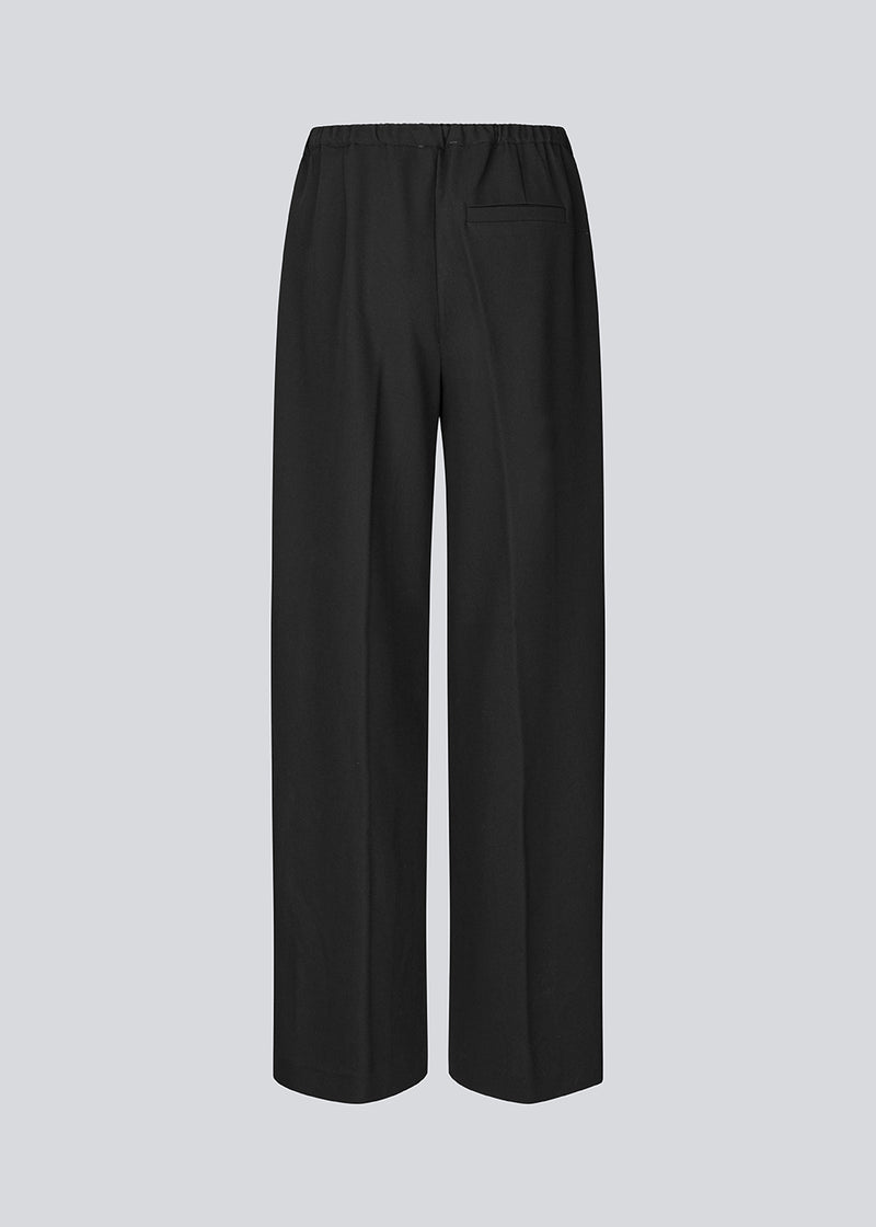 Sorte bukser med brede ben og pressefold. Ridermd pants har sidelommer og elastisk talje – stilrene og komfortable på én gang.