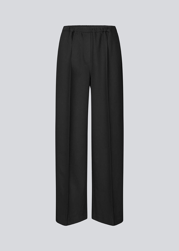 Sorte bukser med brede ben og pressefold. Ridermd pants har sidelommer og elastisk talje – stilrene og komfortable på én gang.