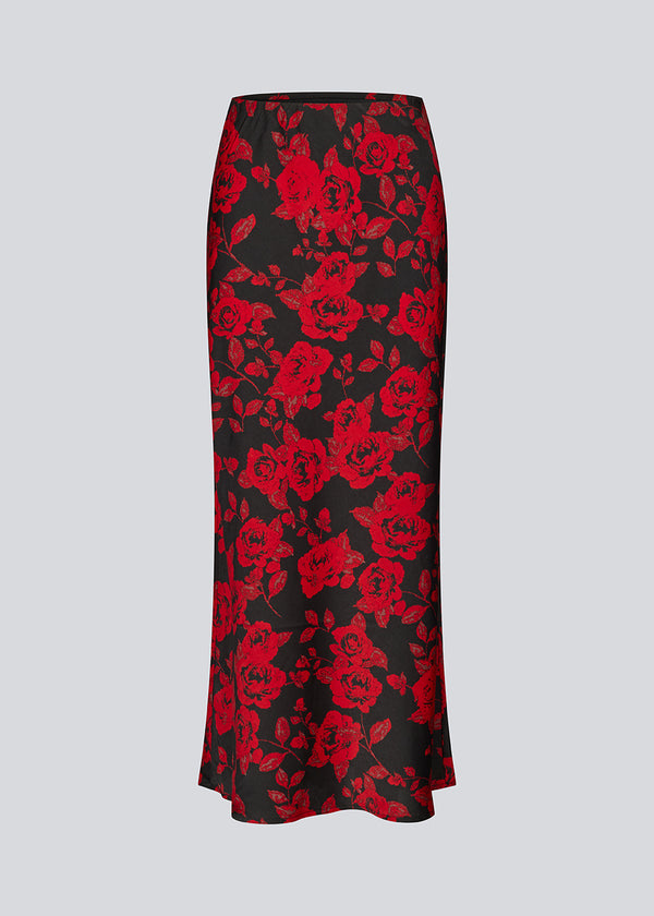 Lang nederdel i et smukt rosenprint. Ruthiemd skirt har elastik i taljen og er lavet i genanvendt polyester– &nbsp;en klassisk og elegant style.