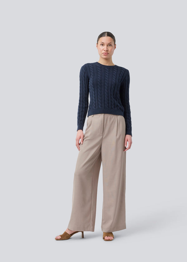 Tætsiddende strik med rund hals i 100% økologisk bomuld. Sabremd o-neck er lavet i kabelstrik og har et broderet brystlogo. Modellen er 175 cm og har en str s/36 på.