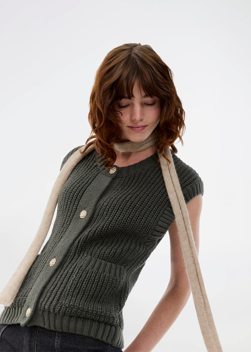 Elegant strikket vest i mørkegrøn med rund hals og dekorative knapper foran. Scottmd vest er designet i strukturerede strik og ribkanter som giver et moderne og feminint udtryk. Perfekt alene eller stylet over en skjorte for et sofistikeret lag-på-lag look.
