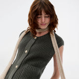 Elegant strikket vest i mørkegrøn med rund hals og dekorative knapper foran. Scottmd vest er designet i strukturerede strik og ribkanter som giver et moderne og feminint udtryk. Perfekt alene eller stylet over en skjorte for et sofistikeret lag-på-lag look.
