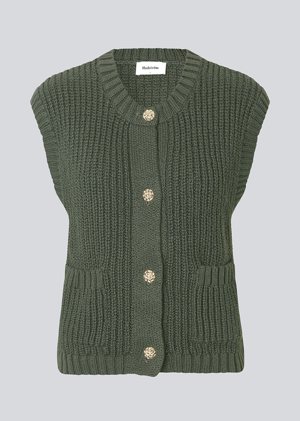Elegant strikket vest i mørkegrøn med rund hals og dekorative knapper foran. Scottmd vest er designet i strukturerede strik og ribkanter som giver et moderne og feminint udtryk. Perfekt alene eller stylet over en skjorte for et sofistikeret lag-på-lag look.
