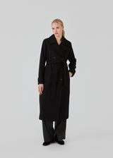 Klassisk, dobbeltradet uldfrakke i sort med krave og revers. ShayMD coat har bredt taljebælte, skulderstropper, brede manchetter og stormflap. Med for og slids bagpå.