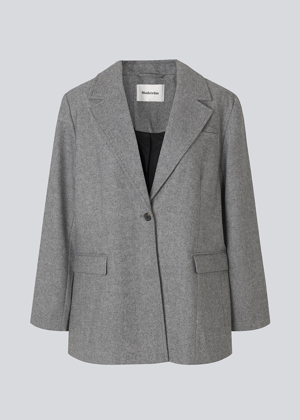 Grå blazer i uldblanding. Simonmd blazer har krave, lange ærmer og to rummelige lommer. Den lukkes med en enkel, synlig knap og er perfekt som overgangsjakke eller som et varmt lag over en t-shirt i vintermånederne.