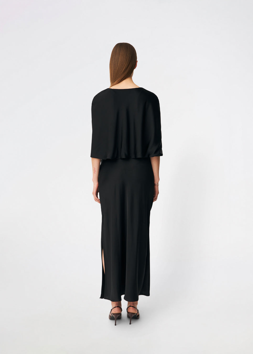 Tailormd Cape er en elegant satin-cape, der tilfører et raffineret og dramatisk udtryk til ethvert outfit. Designet falder let over skuldrene og lukkes foran med en dekorativ knudedetalje, som skaber et blødt, flydende fald. Brug den over en kjole til særlige anledninger eller som et eksklusivt lag over en enkel top for et sofistikeret look.&nbsp;