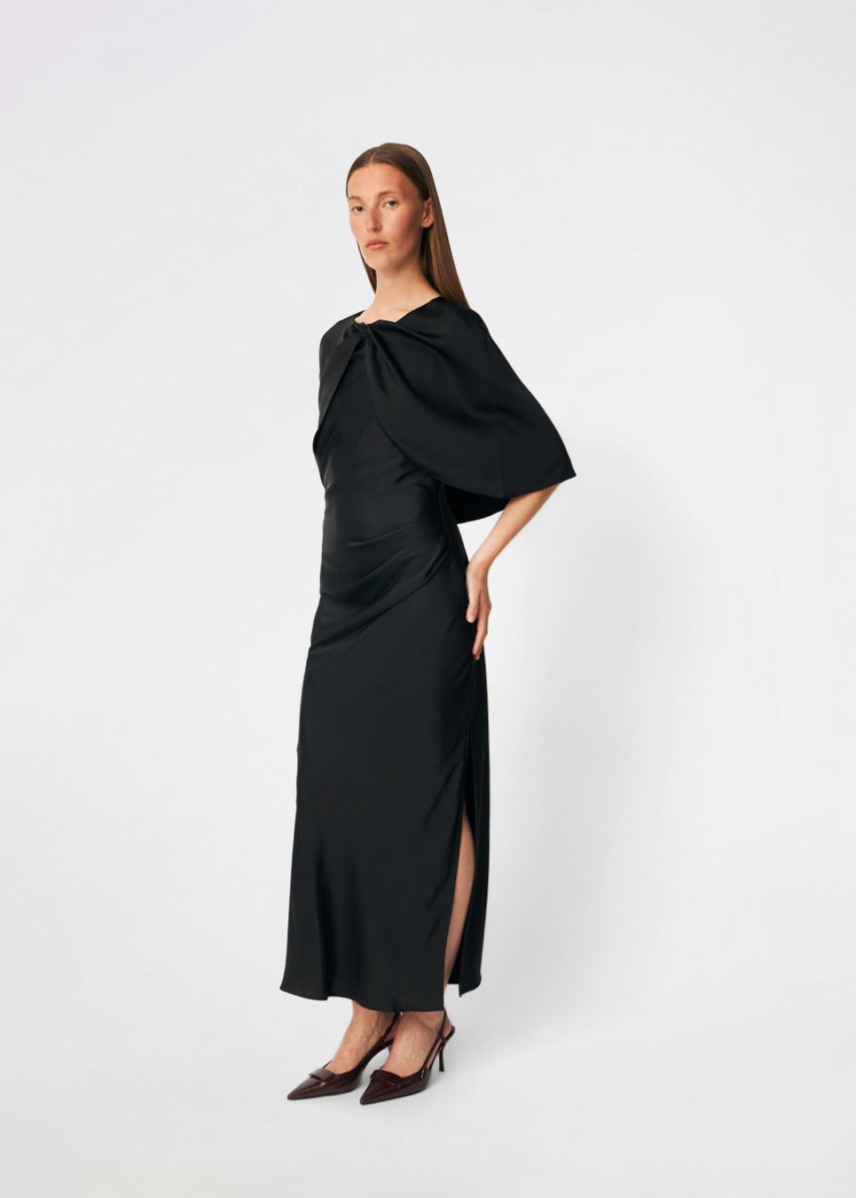 Tailormd Cape er en elegant satin-cape, der tilfører et raffineret og dramatisk udtryk til ethvert outfit. Designet falder let over skuldrene og lukkes foran med en dekorativ knudedetalje, som skaber et blødt, flydende fald. Brug den over en kjole til særlige anledninger eller som et eksklusivt lag over en enkel top for et sofistikeret look.&nbsp;