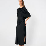 Tailormd Cape er en elegant satin-cape, der tilfører et raffineret og dramatisk udtryk til ethvert outfit. Designet falder let over skuldrene og lukkes foran med en dekorativ knudedetalje, som skaber et blødt, flydende fald. Brug den over en kjole til særlige anledninger eller som et eksklusivt lag over en enkel top for et sofistikeret look.&nbsp;