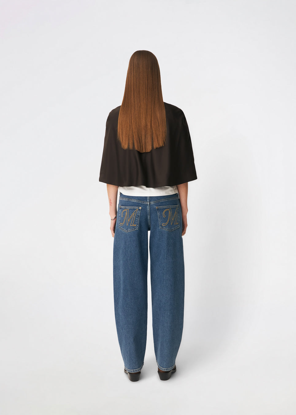 Tailormd Cape er en elegant satin-cape, der tilfører et raffineret og dramatisk udtryk til ethvert outfit. Designet falder let over skuldrene og lukkes foran med en dekorativ knudedetalje, som skaber et blødt, flydende fald. Brug den over en kjole til særlige anledninger eller som et eksklusivt lag over en enkel top for et sofistikeret look. Modellen er 175 cm høj og bruger størrelse S/36.