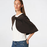 Tailormd Cape er en elegant satin-cape, der tilfører et raffineret og dramatisk udtryk til ethvert outfit. Designet falder let over skuldrene og lukkes foran med en dekorativ knudedetalje, som skaber et blødt, flydende fald. Brug den over en kjole til særlige anledninger eller som et eksklusivt lag over en enkel top for et sofistikeret look. Modellen er 175 cm høj og bruger størrelse S/36.