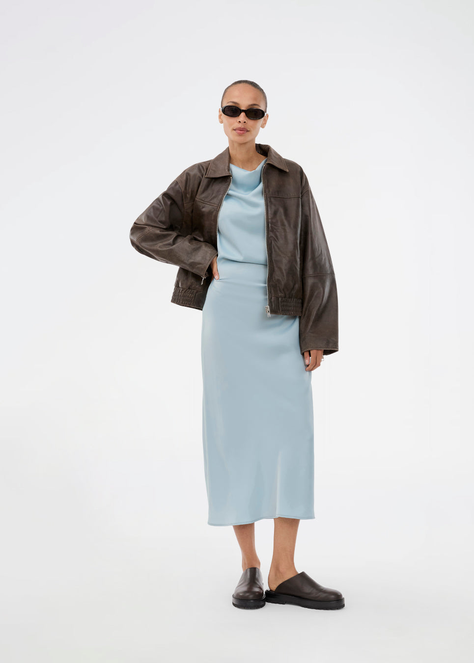 Lang ærmeløs blå kjole med rynkedetalje i satin. TailorMD dress har en høj hals, usynlig lynlås i ryggen og en slids i siden. 