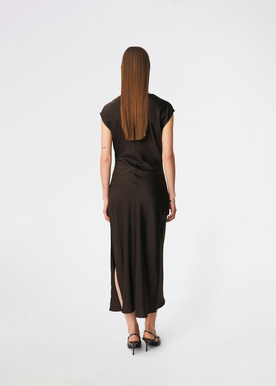 Elegant satinmaxikjole med et sofistikeret udtryk. Tailormd dress er designet i en figursyet silhuet med en blød draperet halsudskæring, korte cap-ærmer og diskrete rynkedetaljer i taljen, der fremhæver den flatterende pasform. Den glatte satinfinish og den lange, flydende silhuet gør kjolen til et elegant valg til både festlige anledninger og særlige begivenheder. Modellen er 175 cm og har en str S/36 på.