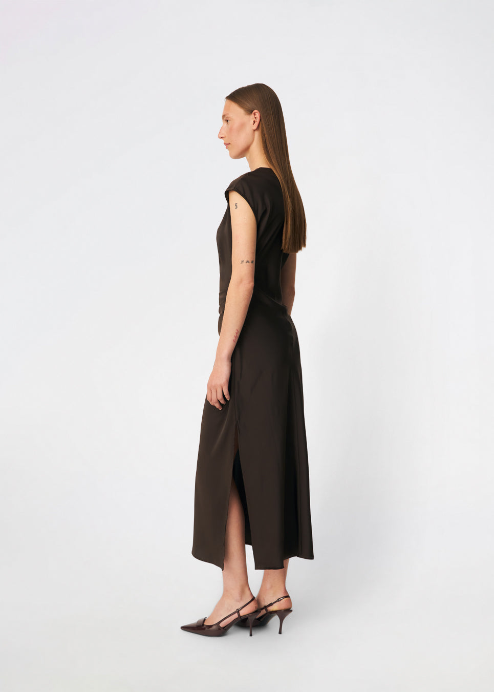 Elegant satinmaxikjole med et sofistikeret udtryk. Tailormd dress er designet i en figursyet silhuet med en blød draperet halsudskæring, korte cap-ærmer og diskrete rynkedetaljer i taljen, der fremhæver den flatterende pasform. Den glatte satinfinish og den lange, flydende silhuet gør kjolen til et elegant valg til både festlige anledninger og særlige begivenheder. Modellen er 175 cm og har en str S/36 på.