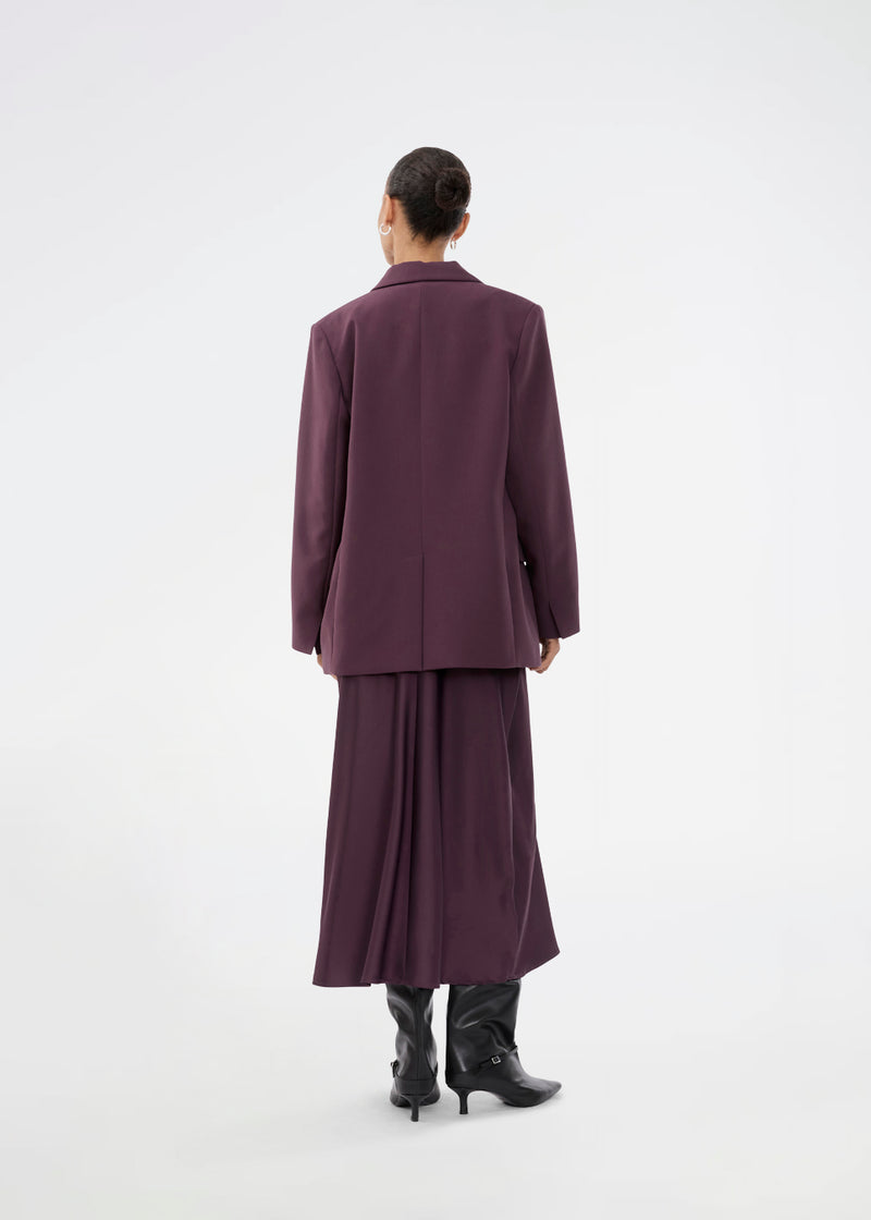 Mørklilla lang ærmeløs kjole med rynkedetalje i satin. TailorMD dress har en høj hals, usynlig lynlås i ryggen og en slids i siden. Modellen er 175 cm og har en str S/36 på.

