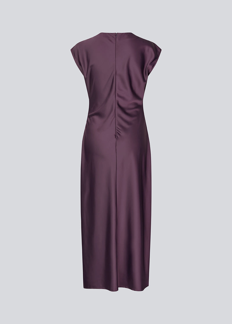 Mørklilla lang ærmeløs kjole med rynkedetalje i satin. TailorMD dress har en høj hals, usynlig lynlås i ryggen og en slids i siden. Modellen er 175 cm og har en str S/36 på.
