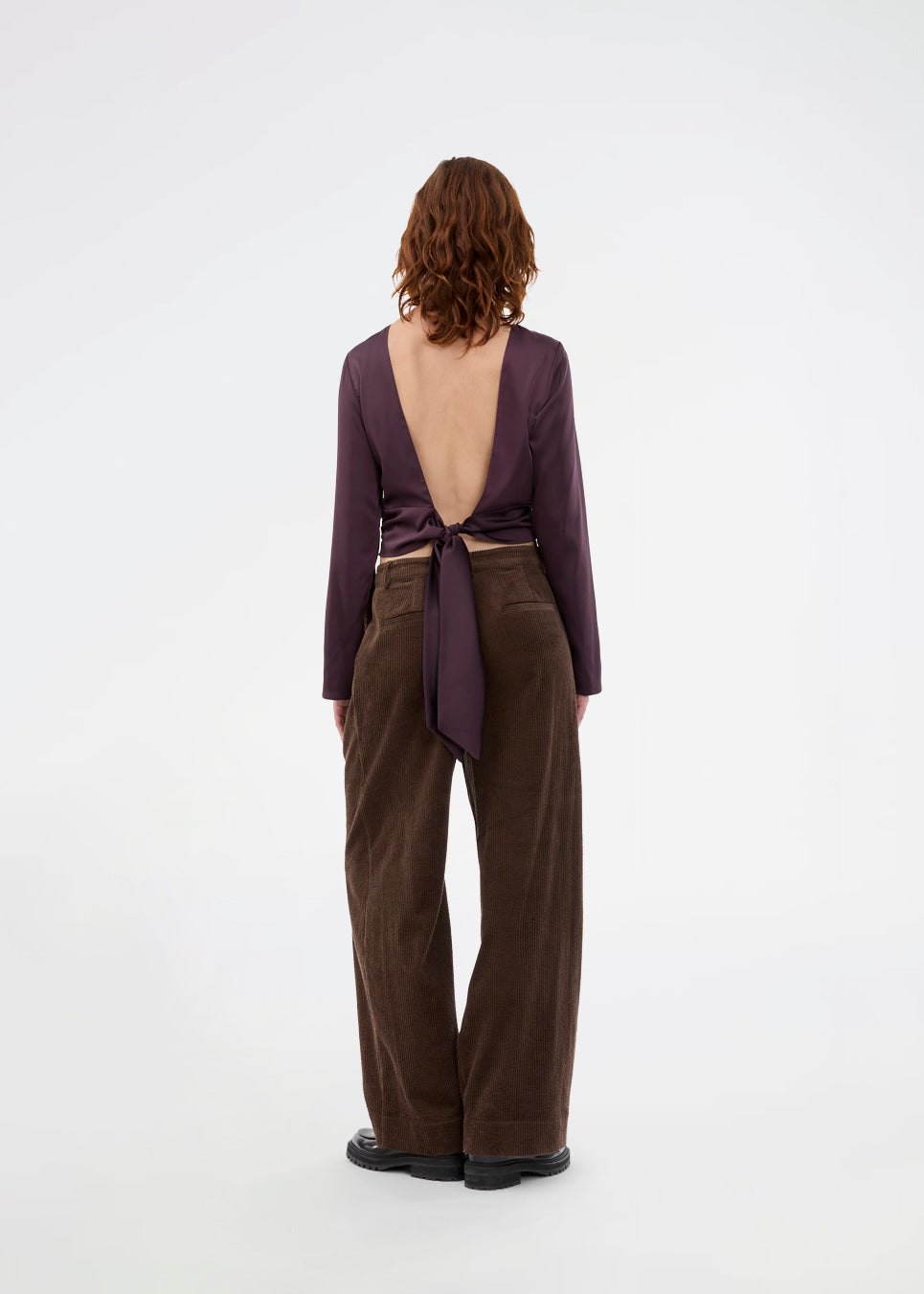 Langærmet top i satin. TailotMD top &nbsp;har en flatterende åben ryg og bindebånd, der giver den et elegant og feminint udtryk. Modellen er 177 cm og har en str S/36 på.