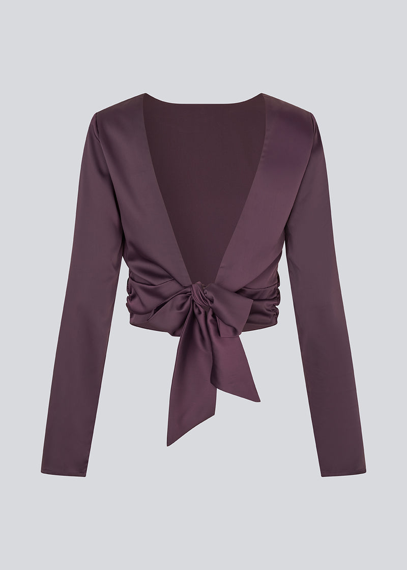 Langærmet top i satin. TailotMD top &nbsp;har en flatterende åben ryg og bindebånd, der giver den et elegant og feminint udtryk. Modellen er 177 cm og har en str S/36 på.