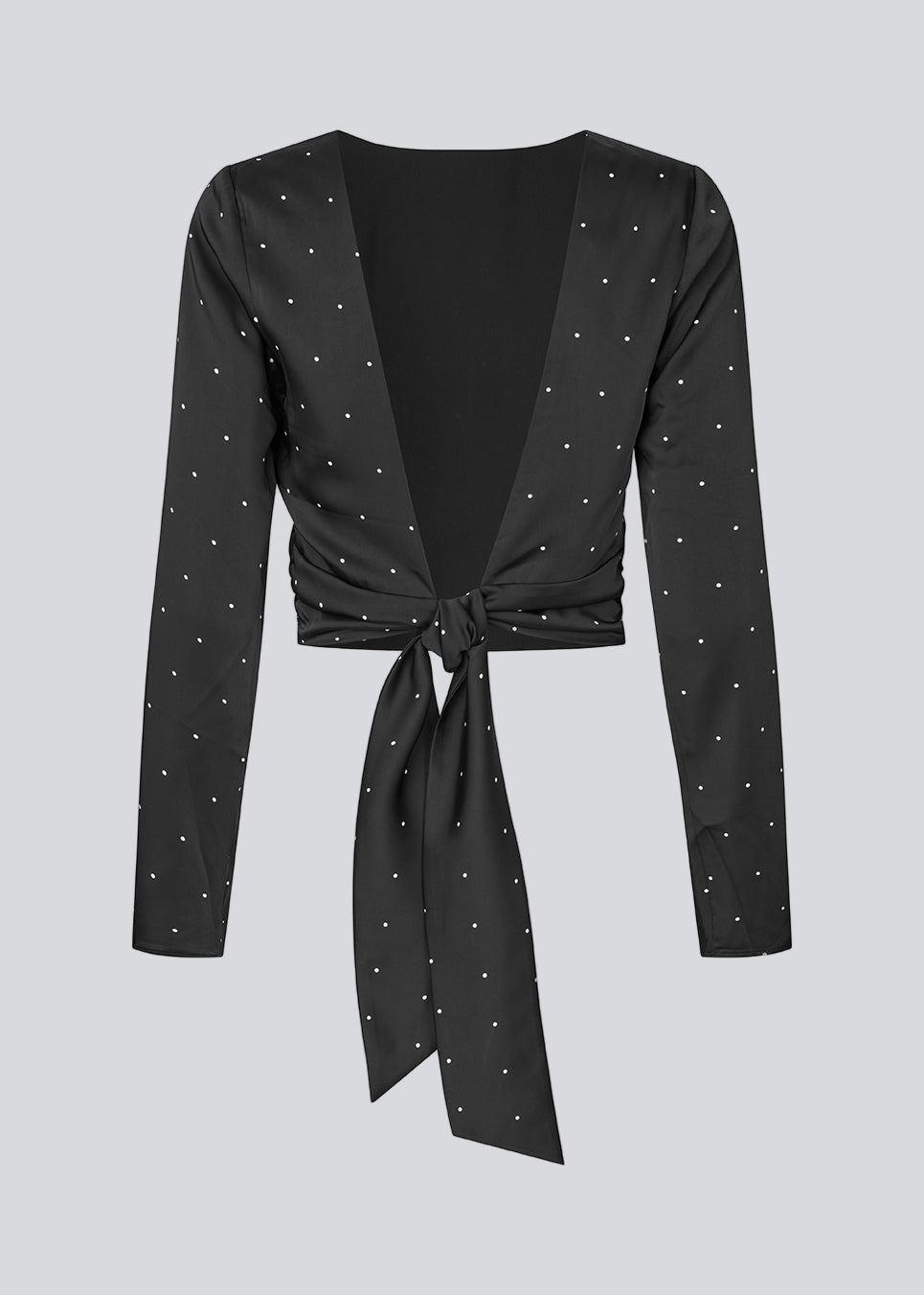 Langærmet top i satin i sort med hvide små prikker. Tailormd print LS top har en flatterende åben ryg og bindebånd, der giver den et elegant og feminint udtryk. Modellen er 177 cm og har en str S/36 på.
