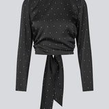 Langærmet top i satin i sort med hvide små prikker. Tailormd print LS top har en flatterende åben ryg og bindebånd, der giver den et elegant og feminint udtryk. Modellen er 177 cm og har en str S/36 på.