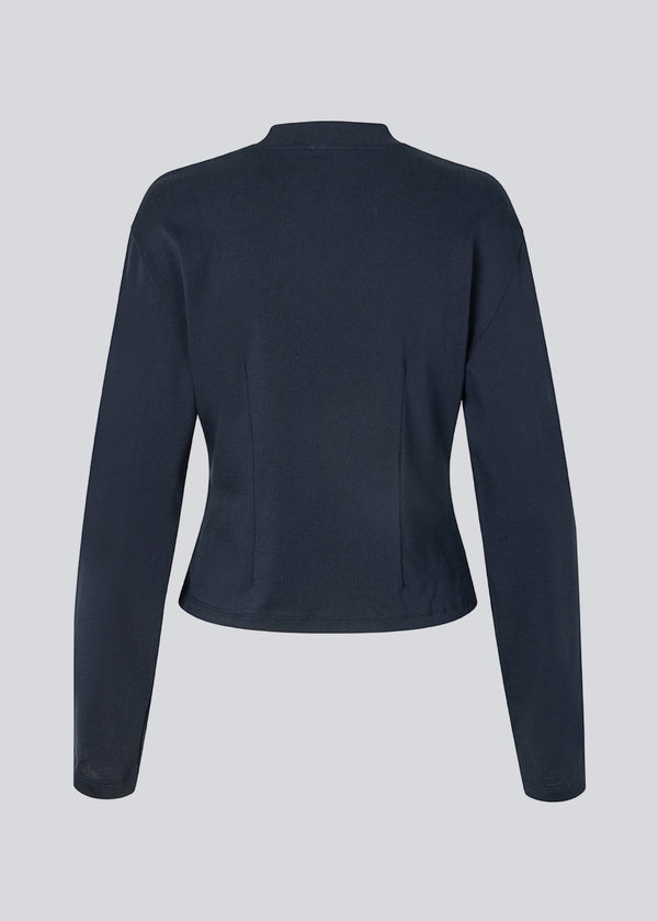 Let cropped langærmet t-shirt i mørkeblå i 100% økologisk bomuld. Tampamd LS t-shirt har en rund hals, lange ærmer og er figursyet.