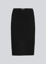 Enkel, stilren og tætsiddende nederdel. Tanny skirt i farven sort går til knæene og har en lille slids bagpå. Det strækbare materiale skaber en perfekt pasform. Modellen er 174 cm og har en størrelse S/36 på