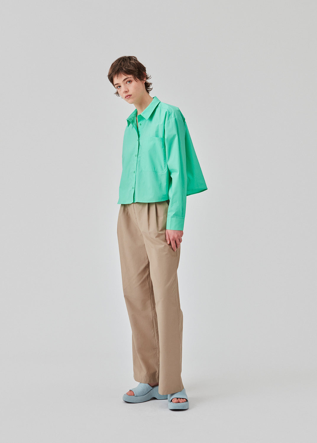 Skjorte i farven Calm Jade i økologisk bomuldspoplin med cropped længde. TapirMD cropped shirt har krave og knapper foran, samt brystlomme. Lav skuldersøm og lange ærmer med manchet og knap. Broderet logo foran. Modellen er 177 cm og har en størrelse S/36 på.