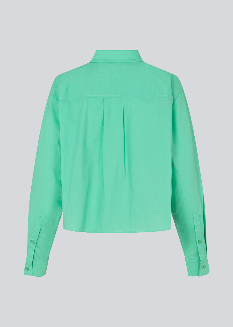 Skjorte i farven Calm Jade i økologisk bomuldspoplin med cropped længde. TapirMD cropped shirt har krave og knapper foran, samt brystlomme. Lav skuldersøm og lange ærmer med manchet og knap. Broderet logo foran. Modellen er 177 cm og har en størrelse S/36 på.