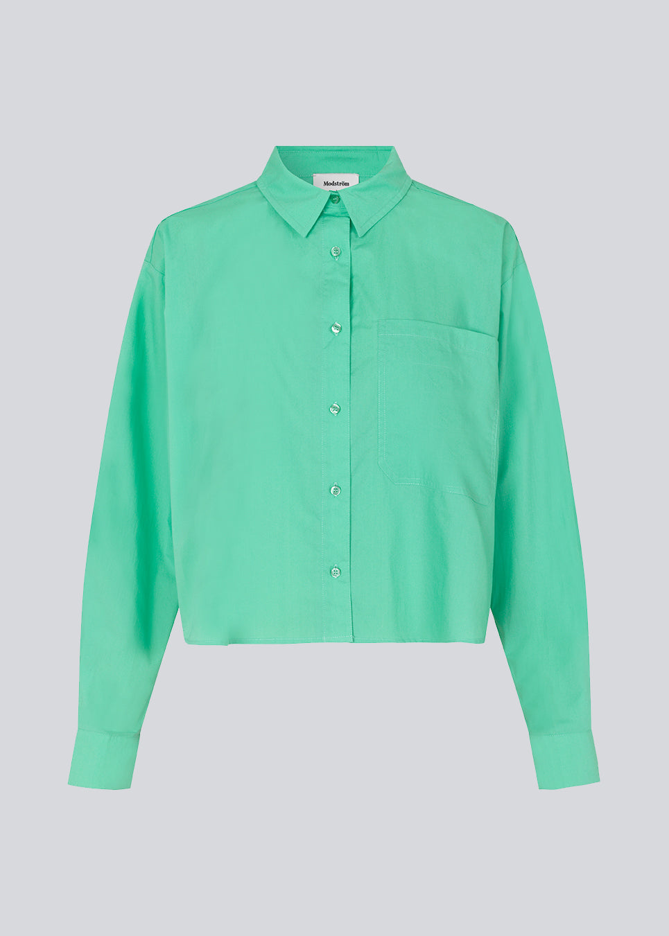 Skjorte i farven Calm Jade i økologisk bomuldspoplin med cropped længde. TapirMD cropped shirt har krave og knapper foran, samt brystlomme. Lav skuldersøm og lange ærmer med manchet og knap. Broderet logo foran. Modellen er 177 cm og har en størrelse S/36 på.
