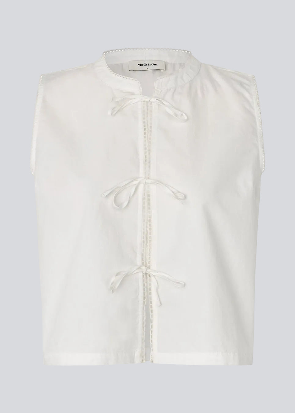 Ærmeløs top i en blød bomuldskvalitet. Tessamd top har bindelukning foran, fine kantdetaljer og en enkel, afslappet silhuet. Et let og alsidigt design, der kombinerer feminine detaljer med et moderne, minimalistisk udtryk.