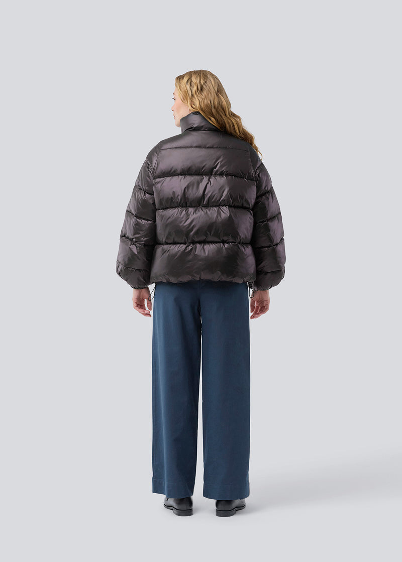 Brun dunjakke med høj hals i 100% genanvendt polyester.&nbsp; Tetrismd jacket har en lynlåslukning og en justerbar elastik i ærmet. Modellen er 175 cm og har en str. s/36 på.
