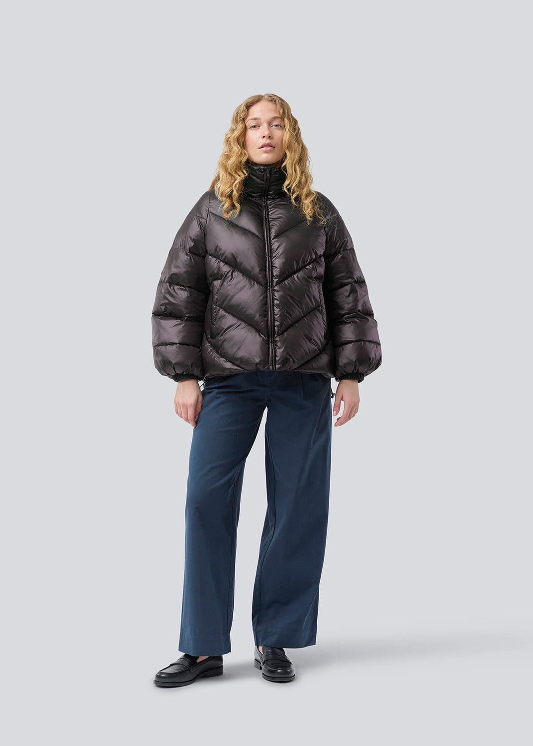 Brun dunjakke med høj hals i 100% genanvendt polyester.&nbsp; Tetrismd jacket har en lynlåslukning og en justerbar elastik i ærmet. Modellen er 175 cm og har en str. s/36 på.