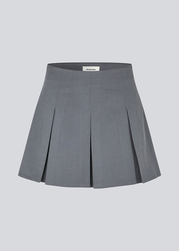 Kort grå nederdel med læg i struktureret materiale. TianaMD skirt har en usynlig lynlås i siden.