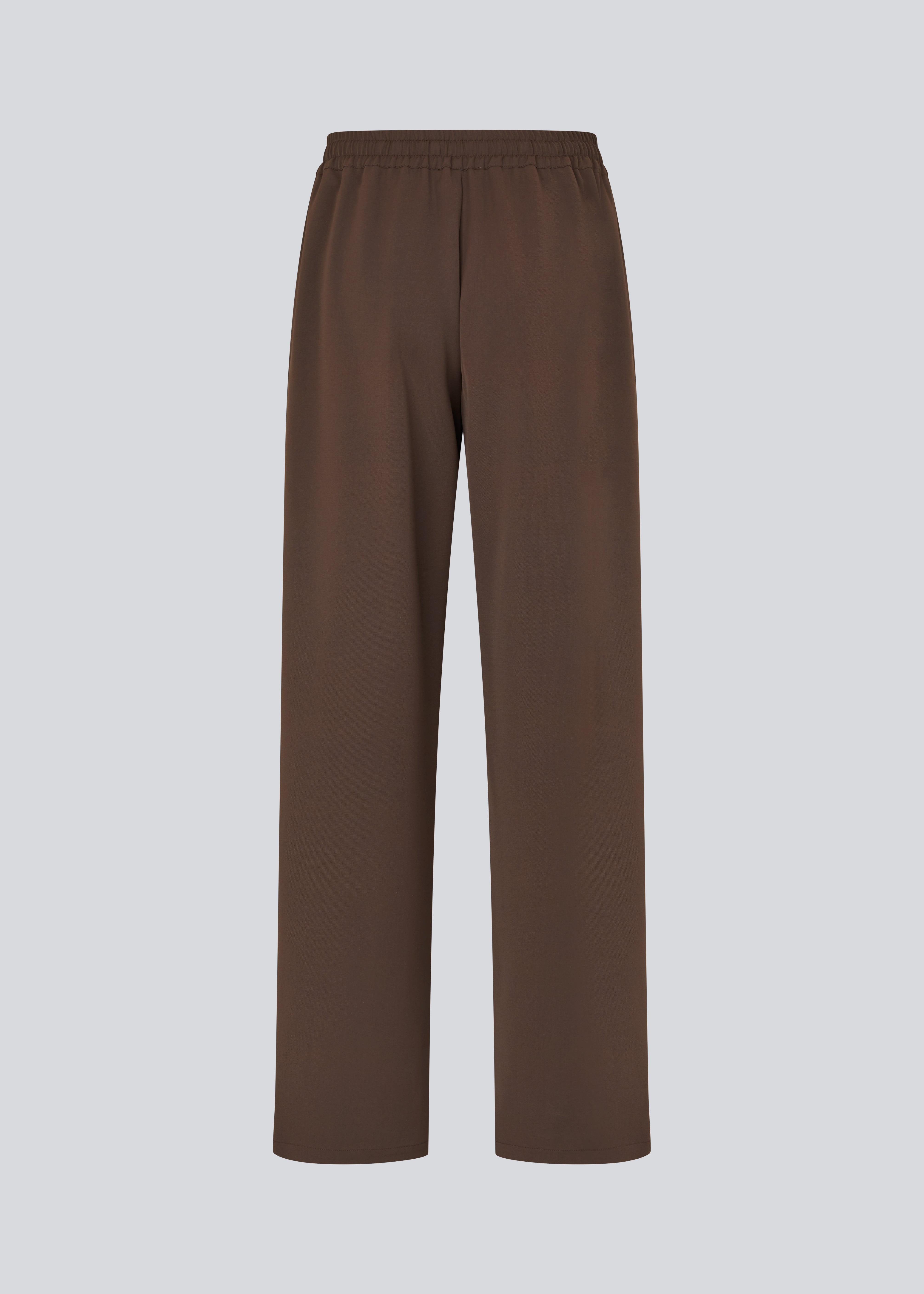 Løse brune bukser med bred benvidde og afslappet pasform. Bukserne har elastisk linning med snøre, der sikrer en behagelig og justerbar talje. Langs siderne løber hvide striber, som tilføjer et sporty og moderne twist til det ellers klassiske design. Perfekte til både afslappet hverdagsbrug og mere stilfulde outfits – nemme at style med alt fra t-shirts til skjorter.