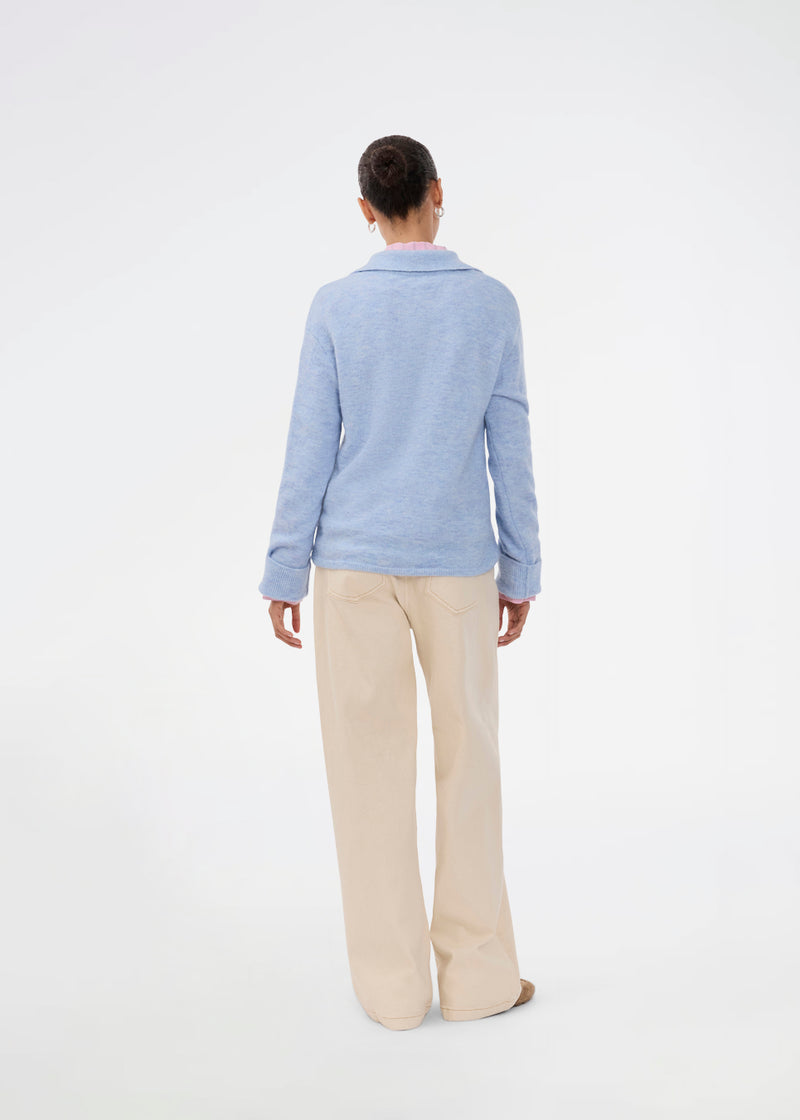 Strikket polo i blå med lange brede ærmer. Treemd polo har en stolpelukning og 4 knapper. Modellen er 175 cm og har en str. S/36 på.