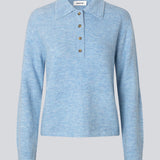 Strikket polo i blå med lange brede ærmer. Treemd polo har en stolpelukning og 4 knapper. Modellen er 175 cm og har en str. S/36 på.