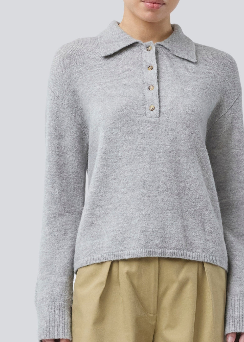 Strikket polo i grå med lange brede ærmer. Treemd polo har en stolpelukning og 4 knapper. Modellen er 175 cm og har en str. S/36 på.