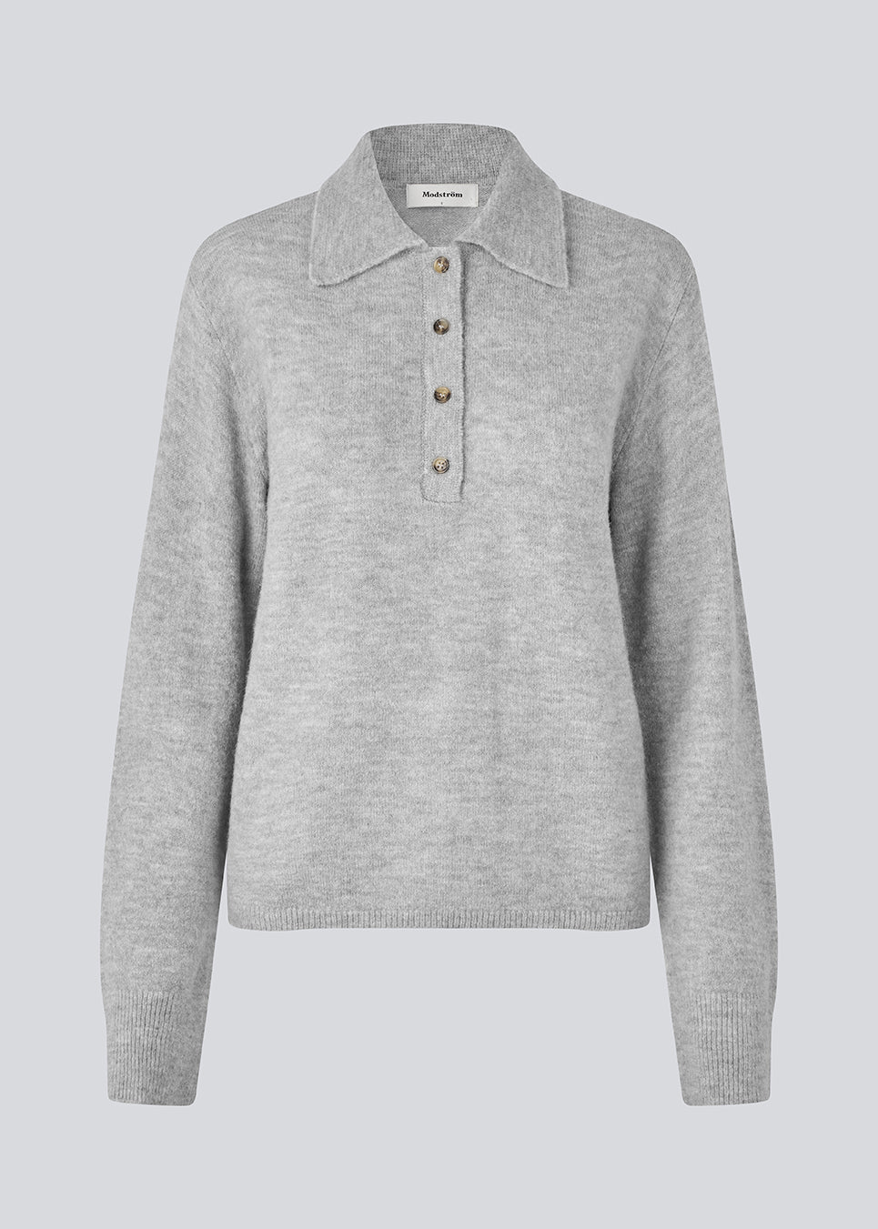 Strikket polo i grå med lange brede ærmer. Treemd polo har en stolpelukning og 4 knapper. Modellen er 175 cm og har en str. S/36 på.